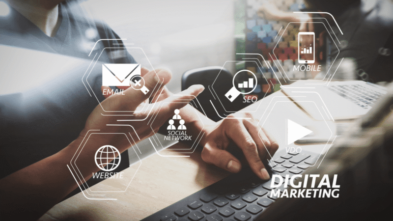 Businessperson using a laptop with digital marketing channel icons