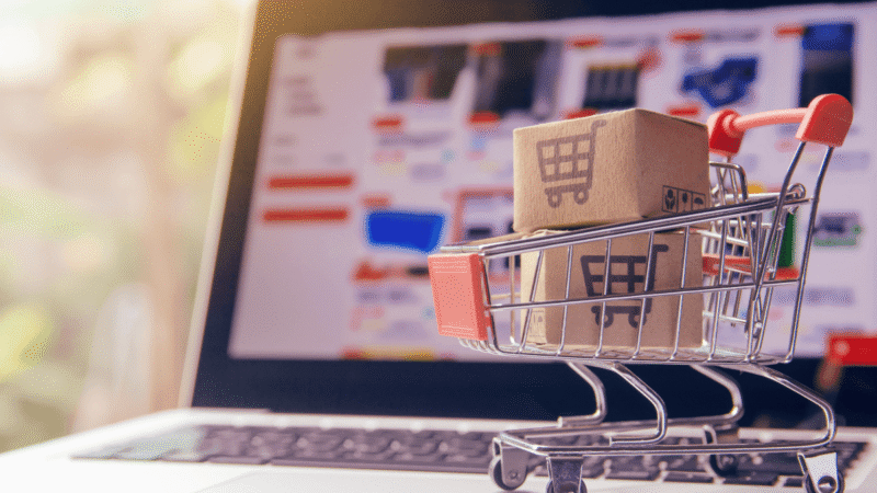 Miniature shopping cart and parcel in front of an online store